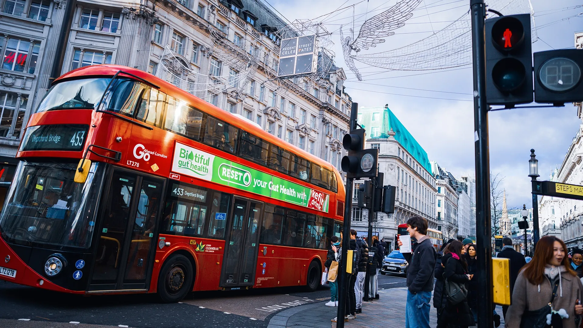 A superside advert passes commuters on a busy London street